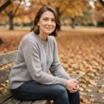 Femme pensive assise sur un banc en automne, exprimant une tristesse apaisée et une résilience intérieure face aux épreuves de la vie