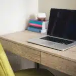 silver and black laptop computer on brown wooden desk beside green leather chair