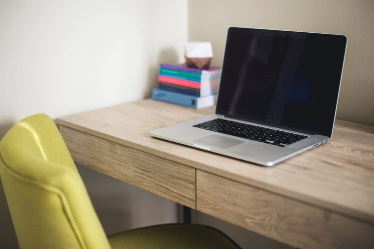 silver and black laptop computer on brown wooden desk beside green leather chair